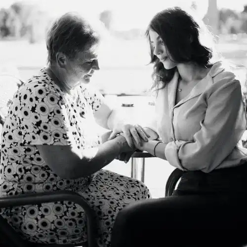 An elderly parent being attended to by a daughter at home