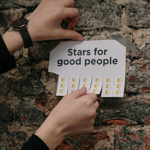 A hand pulling stars from a piece of paper on the wall for being a good person