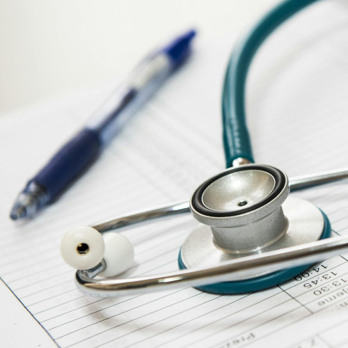 A stethascope lying on a medical chart with a blue pen